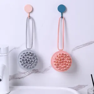 Silicone scalp massage shampoo brushes in pink and gray hanging on bathroom wall
