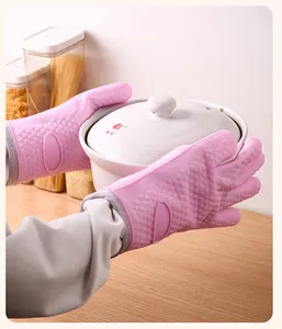 Détail de gants en silicone rose résistant à la chaleur tenant un pot en céramique