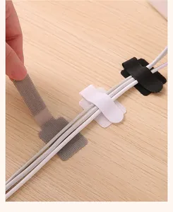 Vue détaillée de serre-câbles velcro adhésifs organisant des fils sur un bureau en bois.
