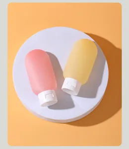 Gros plan de flacons de voyage en silicone rose et jaune sur un support de présentation blanc