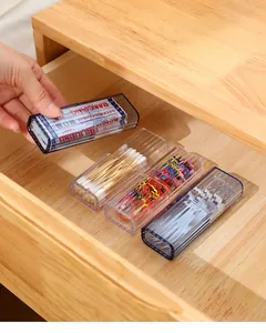 Close-up of mini portable plastic storage box organizing items in a wooden drawer.