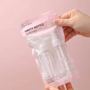Juego de botellas de spray de viaje con dos envases vacíos recargables en bolsa rosa.