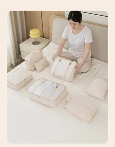 Close-up of cream travel packing cubes set used for organizing clothes on bed