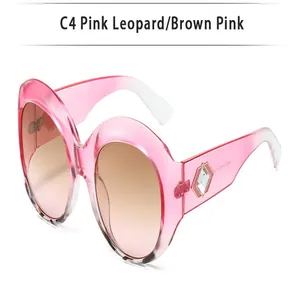 Detail view of oversized round pink sunglasses with brown gradient lenses.