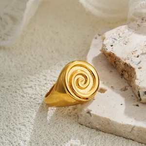 Detailed close-up of a gold-plated signet ring with a unique spiral vortex design.