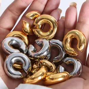 Detailed macro view of chunky gold and silver metallic C-shaped ear cuffs held in palm