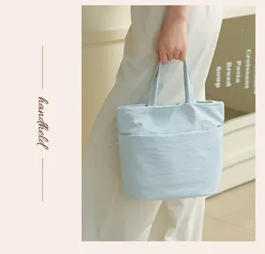 Primer plano de un bolso de viaje de tela Taslan azul claro de gran capacidad en la mano