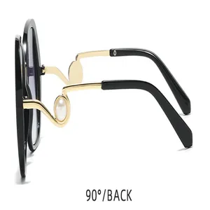 Detailansicht einer modischen Damen-Sonnenbrille mit Goldbügeln und eleganten Perlen
