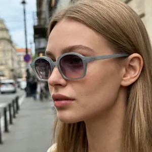 Elegantes gafas de sol ovales pequeñas con montura gris y lentes degradadas violeta.