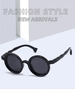 Side detail view of stylish black round-frame sunglasses for children on a grey backdrop