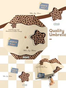 Detalle de paraguas plegable con elegante estampado de leopardo y motivos de estrellas.
