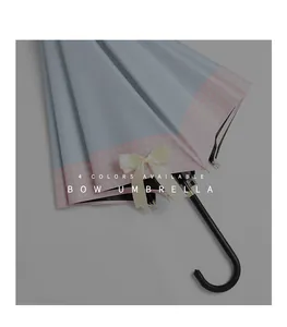 Close-up of light blue long handle umbrella with pink checkered trim and cream bow detail.