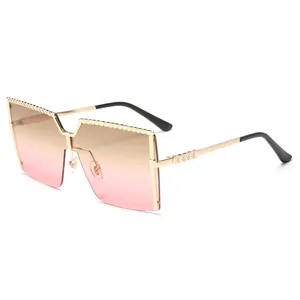 Lunettes de soleil carrées oversize avec monture dorée et verres dégradés roses pour femme.
