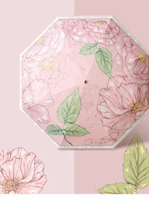 Detailed view of pink folding sun umbrella with elegant floral rose pattern and green leaves
