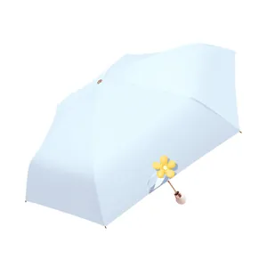 Compact light blue sun and rain umbrella with UV protection and decorative yellow flower charm