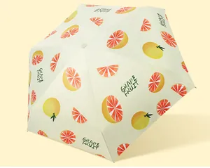 Close-up of portable five-fold umbrella with fresh grapefruit pattern on light yellow fabric