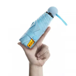 Portable light blue mini foldable UV protection sun umbrella held in hand for scale