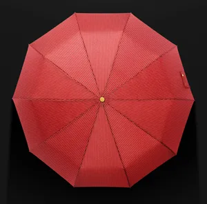 Overhead close-up of a large red automatic folding umbrella with elegant white stripes