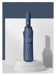 Close-up of a closed blue automatic folding umbrella on a white minimalist studio stage