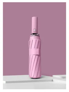 Detail view of closed pink automatic folding umbrella on minimalist white podium