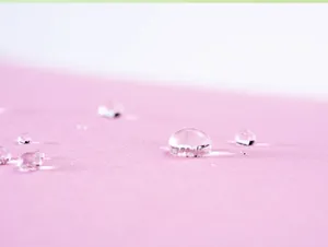 Macro view showing the waterproof lotus effect droplets on high-quality pink umbrella fabric