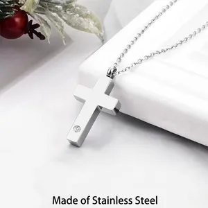 Detalle de un collar con colgante de cruz en acero inoxidable con pequeño cristal