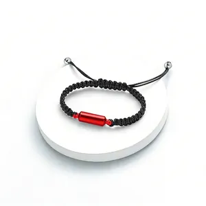 Detailed view of red cylindrical cremation ash pendant on black braided bracelet