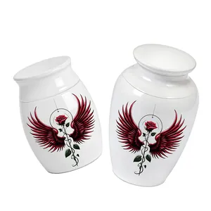 Detail view of two white memorial cremation urns featuring a red rose and wing design.