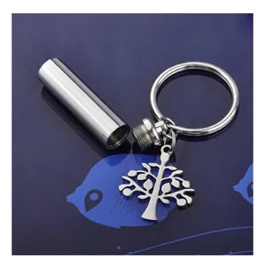 Silver cylindrical cremation urn keychain with tree of life charm for memorial keepsakes.