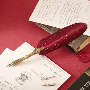 Close-up detail of a vintage red feather dip pen with an antique bronze handle on parchment paper.