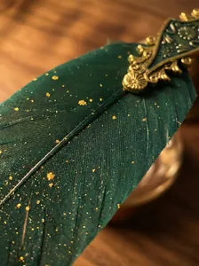 Detailed macro shot of an ornate green feather dip pen with gold filigree and speckles.
