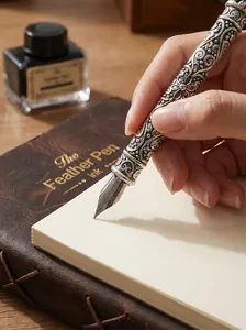 Close-up of hand writing with vintage engraved metal fountain pen on notebook.