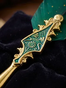 Macro view of a vintage gold engraved metal handle with green enamel on a feather dip pen