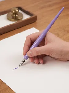 Macro view of hand holding a lavender dip pen with professional G nib drawing on paper