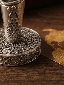 Close-up detail of a vintage silver metal pen stand with intricate embossed patterns