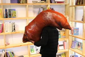 Detailed shot of funny realistic roasted pig trotter plush pillow being held by a person.