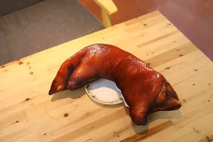 Detailed macro view of a realistic roasted pig trotter shaped plush throw pillow.