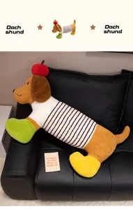 Détail d'un mignon coussin en peluche teckel de dessin animé avec décor de pomme rouge