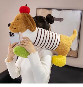 Personne tenant un long oreiller en peluche de chien teckel avec une pomme de dessin animé