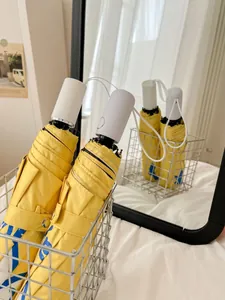 Detail view of compact yellow folding umbrellas in a stylish metal storage basket