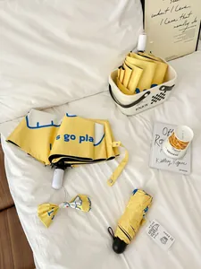 Cute yellow cartoon folding umbrellas set with matching bow on white bed linen