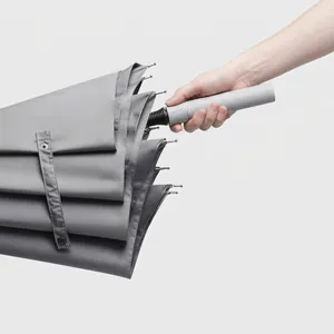 Minimalistischer grauer automatischer Langstiel-Regenschirm wird in der Hand gehalten