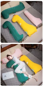 Détail de coussins longs en soie glacée en forme de dinosaure et de girafe au lit