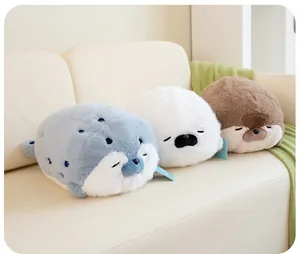 Close-up of three cute soft seal plush toys in blue, white, and brown on a sofa