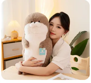 Close-up of a soft plush sea otter toy held by a model in a cozy indoor home setting