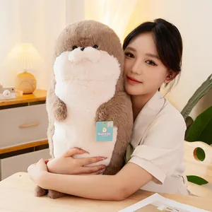 Cute oversized sea otter plush toy being held by a female model in a warm room setting