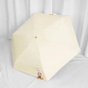 Draagbare beige zonnescherm met UV-bescherming en een schattige decoratieve konijnenpop eraan
