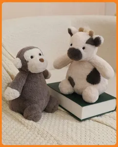 Adorable soft plush monkey and cow stuffed animal toys sitting on a vintage book