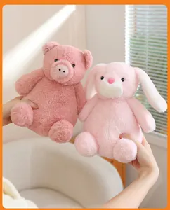 A pair of soft pink bunny and pig plush toys held against a warm indoor sunlight background