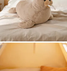 Realistic brown walrus plush toy lying on a cozy bed with soft textile detail